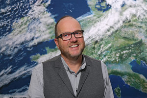 Portrait Frank Kahl vor der Rückwand mit dem Motiv Satellitenbild (Quelle DWD)