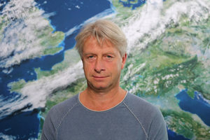 Portrait Rüdiger Manig vor der Rückwand mit dem Motiv Satellitenbild (Quelle DWD)