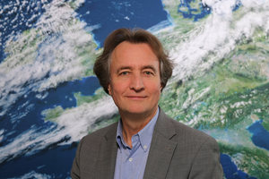 Porträt Uwe Kirsche vor der Rückwand mit dem Motiv Satellitenbild (Quelle DWD)